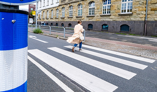 Ene Frau überquert eine Straße mittels Zebrastreifen